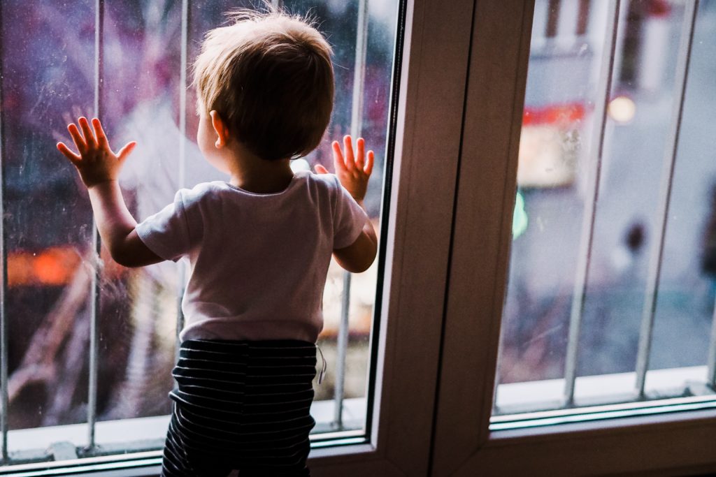 Kind schaut aus dem Fenster
